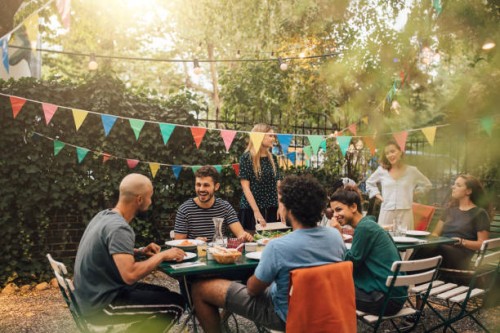 happy multi-ethnic friends talking while having dinner during garden party - garden decoration stock pictures, royalty-free photos & images