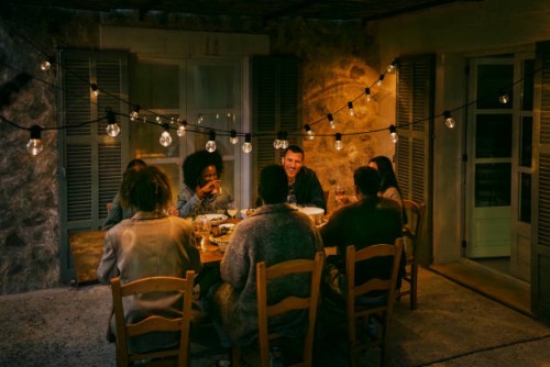 happy multiracial female and male friends sitting at dining table in patio during dinner party at night - garden decoration stock pictures, royalty-free photos & images