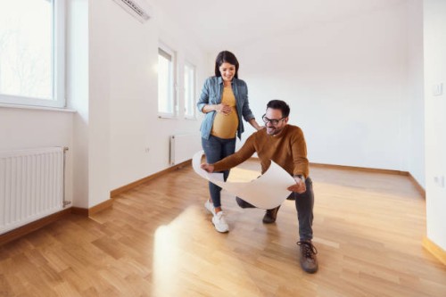 happy pregnant couple analyzing blueprints in their new apartment. - home decoration stock pictures, royalty-free photos & images
