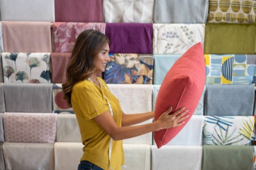 happy saleswoman working at a fabric shop and holding a cushion - home decoration stock pictures, royalty-free photos & images