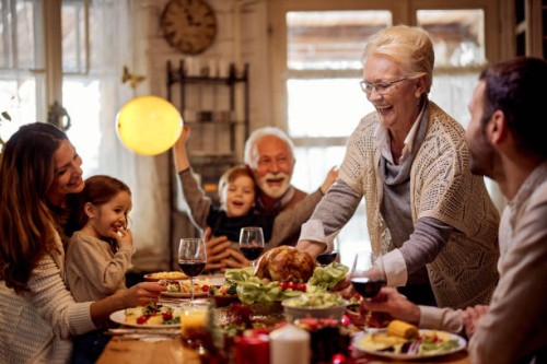 happy senior woman serving a meal to her family in dining room. - home decoration stock pictures, royalty-free photos & images