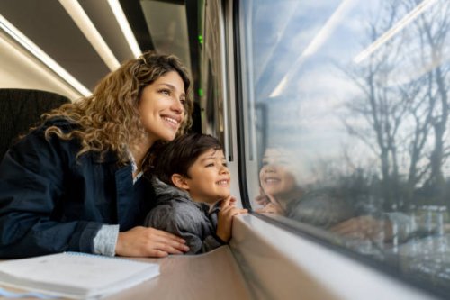 happy single mother and son looking at the window view both smiling while traveling by train - travel stock pictures, royalty-free photos & images