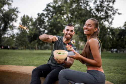 happy sporty couple eating vegetable salad after intensive workout - food stock pictures, royalty-free photos & images