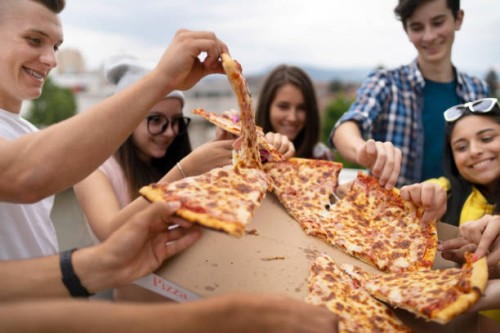 happy students eating pizza together on a party - junk food stock pictures, royalty-free photos & images