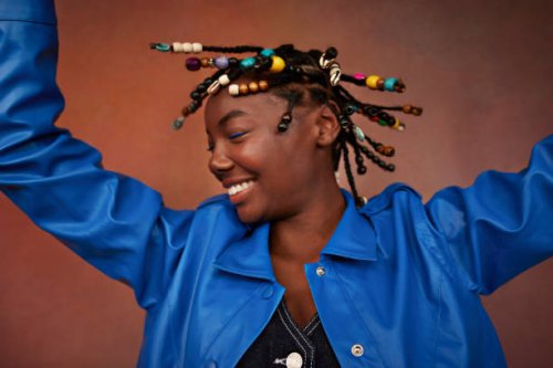happy teenage girl wearing blue jacket shaking head against brown background - hairstyle stock pictures, royalty-free photos & images