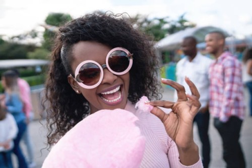 happy woman eating a cotton candy at an amusement park - food stock pictures, royalty-free photos & images