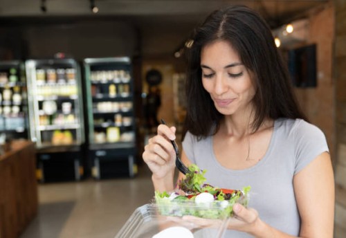 happy woman eating a salad on the go - junk food stock pictures, royalty-free photos & images