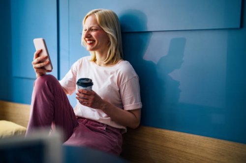 happy woman sitting in a cafe and looking at mobile phone - junk food stock pictures, royalty-free photos & images