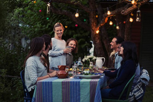 happy woman talking to friends sitting at dinner table in yard - garden decoration stock pictures, royalty-free photos & images