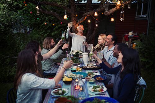 happy woman toasting drink to friends at dining table while enjoying outdoor dinner party - garden decoration stock pictures, royalty-free photos & images
