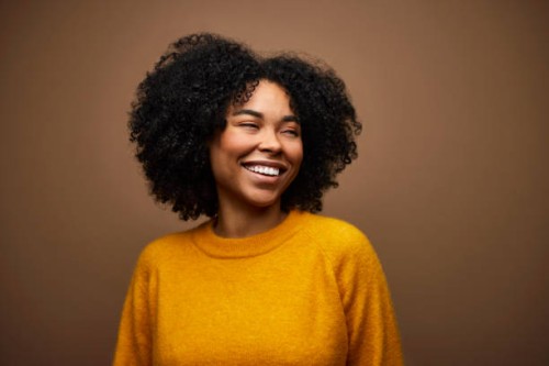happy woman with curly hair against brown background - fashion stock pictures, royalty-free photos & images