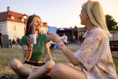 happy women talking while enjoying in drinks at music festival. - concert stock pictures, royalty-free photos & images