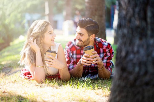 happy young couple drinking coffee in the park - junk food stock pictures, royalty-free photos & images
