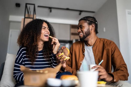 happy young couple eating fast food at home - junk food stock pictures, royalty-free photos & images