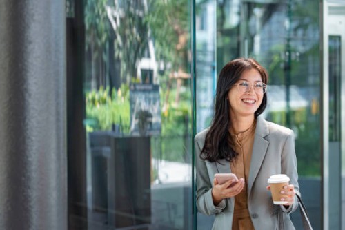 happy young elegant asian businesswoman texting on her smartphone on the go - junk food stock pictures, royalty-free photos & images