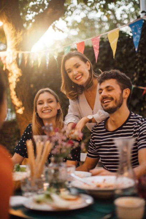 happy young male and female friends at table during dinner party in backyard - garden decoration stock pictures, royalty-free photos & images