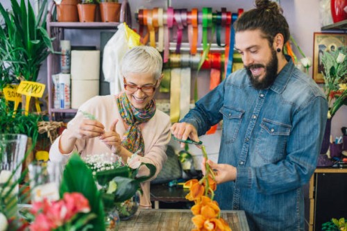 happy young man and a florist trimming flowers - garden decoration stock pictures, royalty-free photos & images