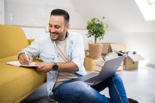 happy young man making a shopping checklist for his new apartment - home decoration stock pictures, royalty-free photos & images