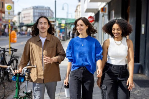 happy young people walking down the city street with a bicycle and smiling - fashion stock pictures, royalty-free photos & images