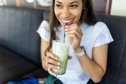 happy young woman having iced matcha latte at cafe - food stock pictures, royalty-free photos & images