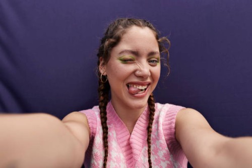 happy young woman winking and sticking tongue out taking selfie - fashion stock pictures, royalty-free photos & images