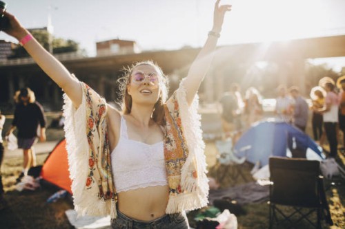 happy young woman with arms raised enjoying at music event during summer - fashion stock pictures, royalty-free photos & images