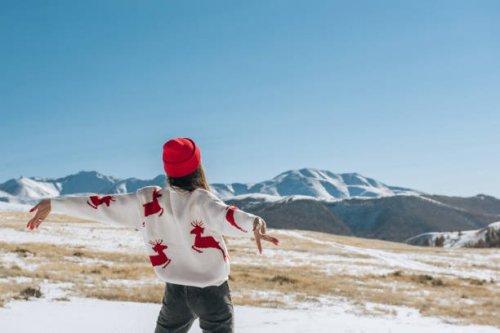 happy young woman with raised hands on the background of blue sky and winter mountains in winter looking at the landscape. christmas travel concept - travel photos et images de collection