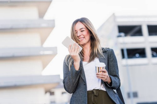 happy young woman with takeaway coffee and cell phone in the city - junk food stock pictures, royalty-free photos & images