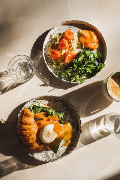 healthy, organic and natural breakfast. croissant, salmon, poached egg, greens, tomato, omelette. glass of water and coffee cup - food stock pictures, royalty-free photos & images