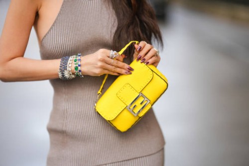 Heart Evangelista wears a yellow Fendi bag, jewelry, bejeweled bracelets, rings, purple nail polish and a gray ribbed dress, outside Fendi during the...