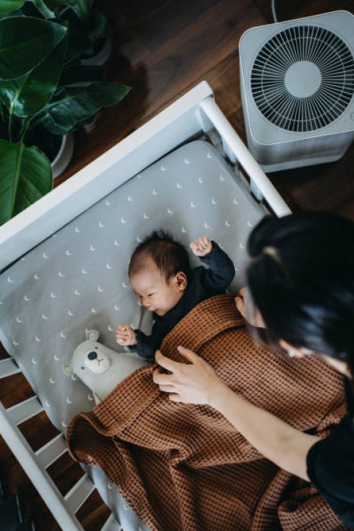 high angle shot of loving young asian mother taking care and tucking in her newborn baby daughter into crib in the nursery. love, care and tenderness. motherhood, parenthood concept - home decoration stockfoto's en -beelden