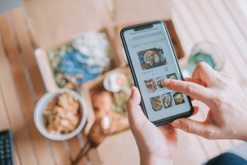high angle view close up asian woman using meal delivery service ordering food online with mobile app on smartphone in the living room at a cozy home - food stock pictures, royalty-free photos & images