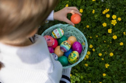 high angle view of a child collecting multicoloured painted easter eggs in a basket made of woven cardboard in a back yard. - garden decoration stock pictures, royalty-free photos & images