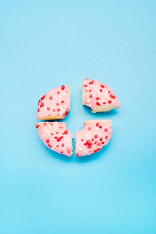 high angle view of a donut divided into four parts on blue background, symbol for pie chart - junk food stock pictures, royalty-free photos & images