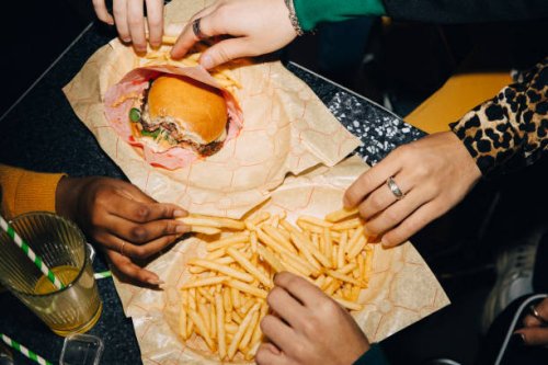high angle view of friends eating burger and french fries at table in cafe - junk food stock pictures, royalty-free photos & images