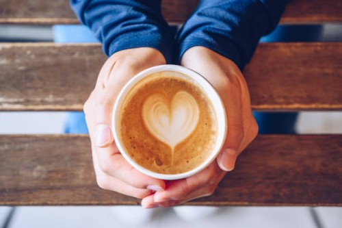 high angle view of someone hands holding a take away cup of hot latte coffee. - junk food stock pictures, royalty-free photos & images