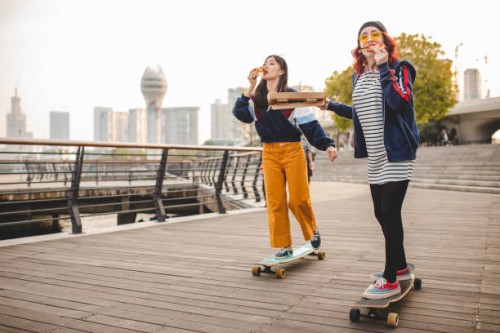 hipster women eating pizza and riding long boards - fashion stock pictures, royalty-free photos & images