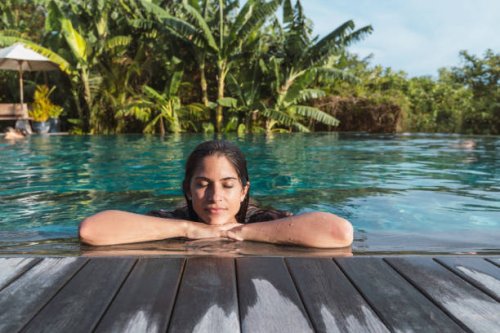hispanic woman at hotel tropical resort sunbathing with palm trees in background - travel stock pictures, royalty-free photos & images