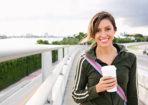 hispanic woman walking outdoors with coffee - junk food stock pictures, royalty-free photos & images
