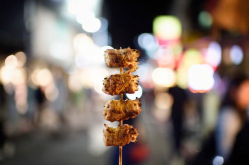 holding a bbq skewer on a street at night - junk food stock pictures, royalty-free photos & images