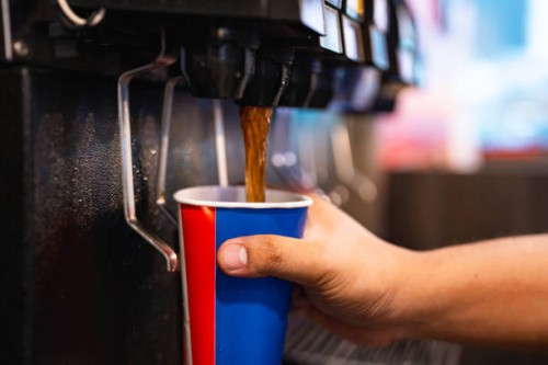 holding a cup at soft drink self service machine pouring cola fizzy drink at a restaurant. - junk food stock pictures, royalty-free photos & images