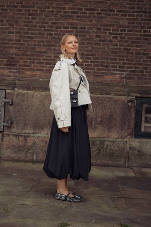 Hollie Mercedes Peters wears black long balloon skirt, white shirt, black tie, black mini bag and black shoes decorated with crystals outside the...