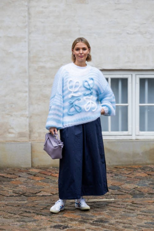 Hollie Mercedes Peters wears blue Loewe knit, wide leg shorts, lavender pink Loewe bag outside Marimekko during the Copenhagen Fashion Week...