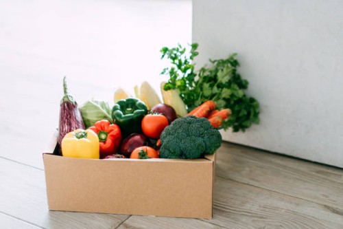 home delivery of a box full of colourful and fresh organic groceries ordered online delivered at the door step - food stock pictures, royalty-free photos & images