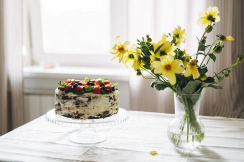 homemade cake with berries and mint leaves on dining table with bouquet of garden flowers at home - garden decoration stock pictures, royalty-free photos & images