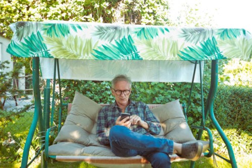 homme âgé utilisant un téléphone intelligent dans le jardin - garden decoration photos et images de collection