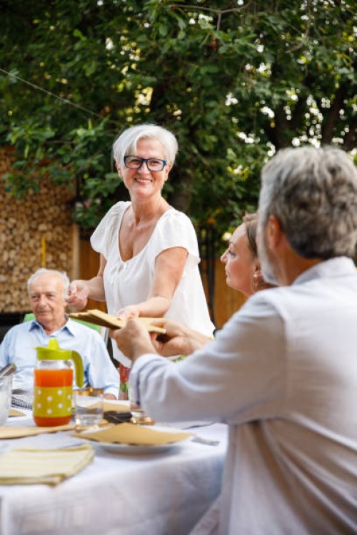 homme tendant une pile de serviettes à son ami qui installe la table - garden decoration photos et images de collection