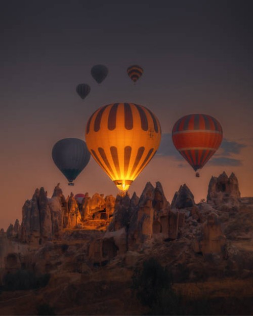 hot air balloons flying over rock formations at sunrise in cappadocia, goreme, turkey - travel stock pictures, royalty-free photos & images