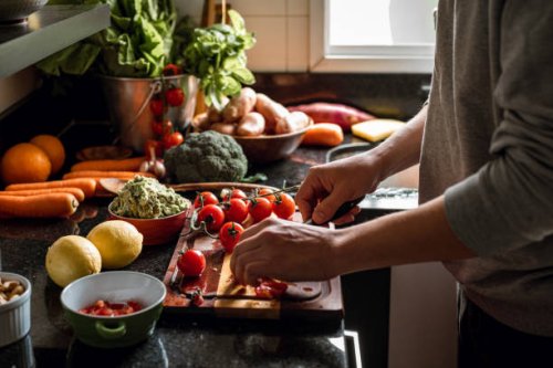 human hands slicing tomatoes over a wooden table for a vegan meal - food stock pictures, royalty-free photos & images
