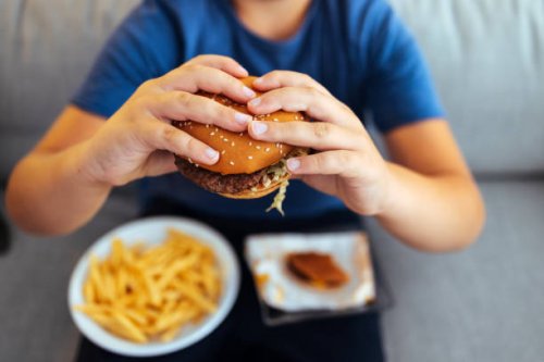 hungry young man holding tasty hamburger - junk food stock pictures, royalty-free photos & images
